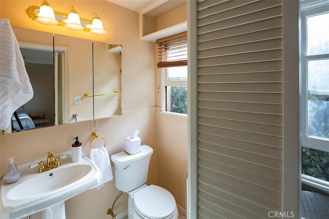 bathroom featuring sink, toilet, and a healthy amount of sunlight