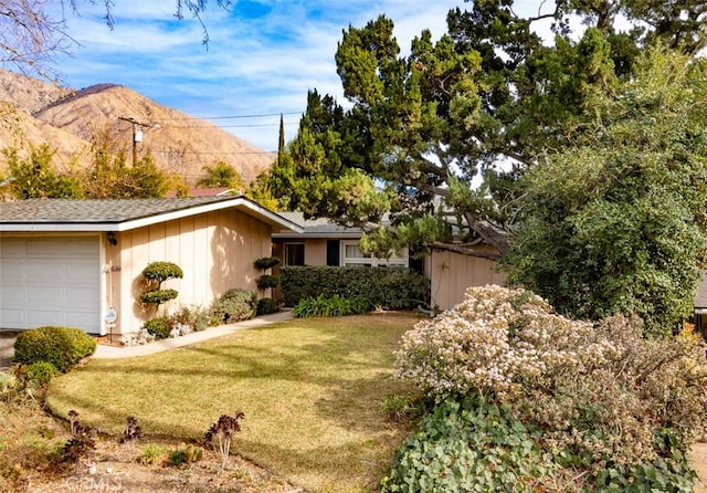 single story home featuring a mountain view, a front yard, and a garage