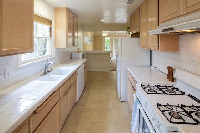 kitchen featuring white appliances, sink, backsplash, ceiling fan, and tile countertops