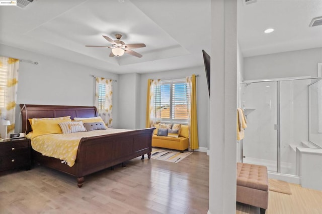 bedroom with a raised ceiling, ceiling fan, and light hardwood / wood-style flooring