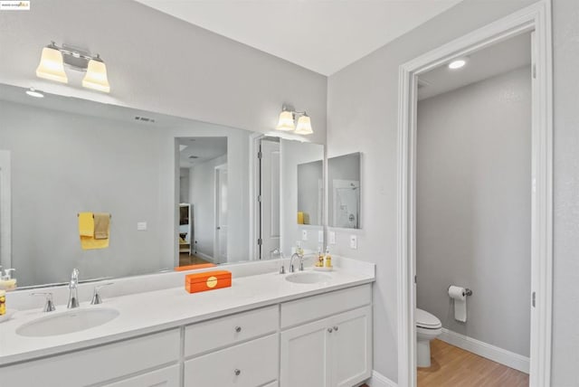 bathroom with hardwood / wood-style flooring, vanity, and toilet