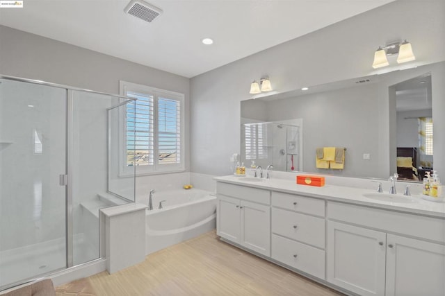 bathroom featuring hardwood / wood-style flooring, vanity, and plus walk in shower