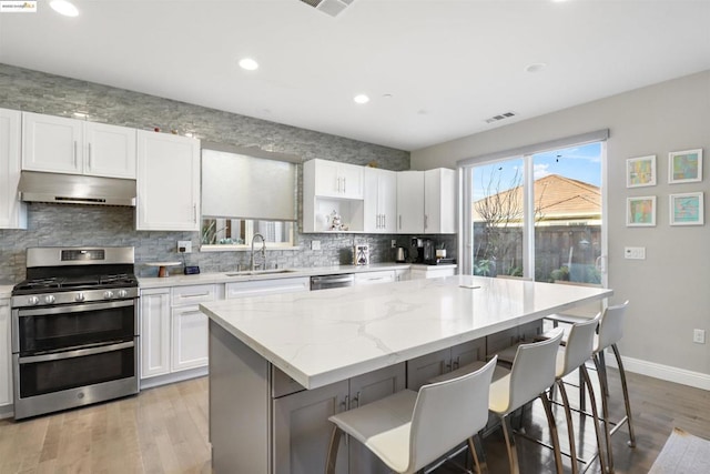 kitchen featuring stainless steel appliances, a center island, white cabinets, and a kitchen breakfast bar