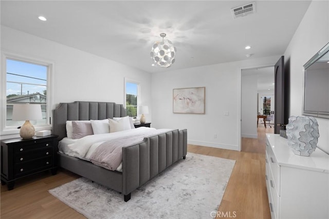 bedroom with light hardwood / wood-style floors and a notable chandelier