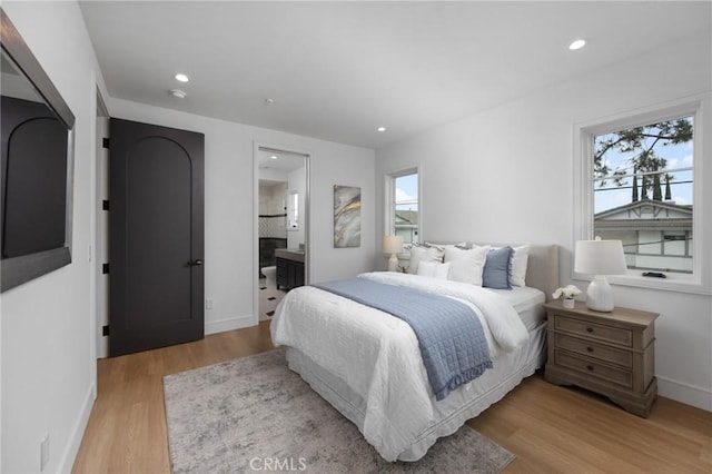 bedroom with light hardwood / wood-style floors and connected bathroom