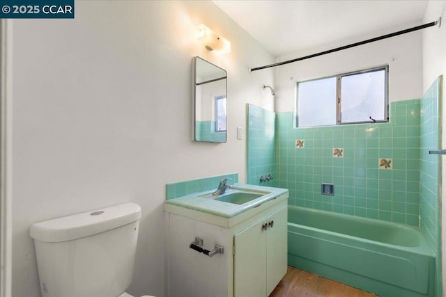 full bathroom featuring hardwood / wood-style floors, toilet, vanity, and tiled shower / bath