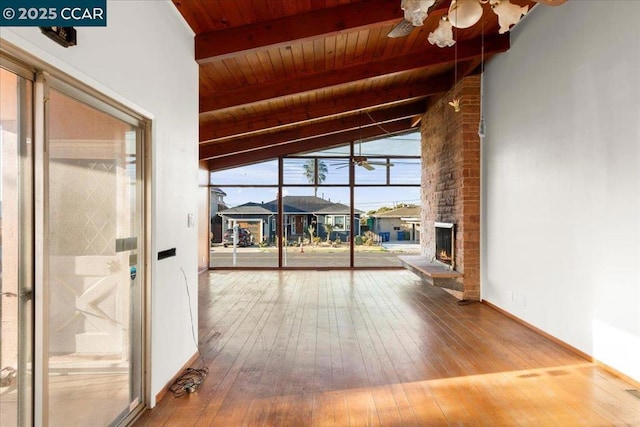 unfurnished living room with ceiling fan, a fireplace, lofted ceiling with beams, hardwood / wood-style flooring, and wood ceiling