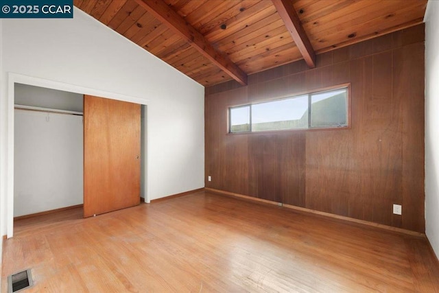 unfurnished bedroom featuring lofted ceiling with beams, wood ceiling, a closet, and hardwood / wood-style flooring