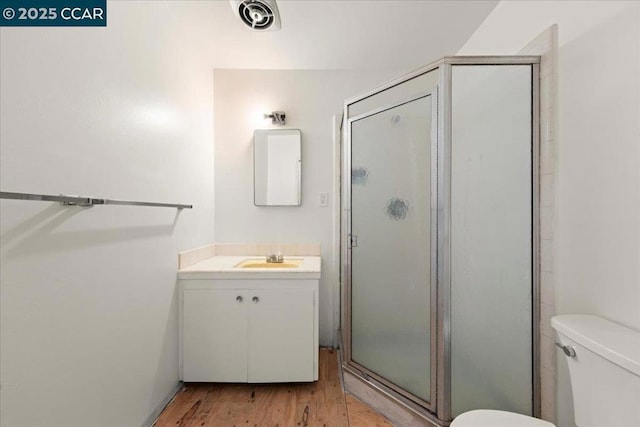 bathroom featuring toilet, vanity, a shower with door, and hardwood / wood-style flooring