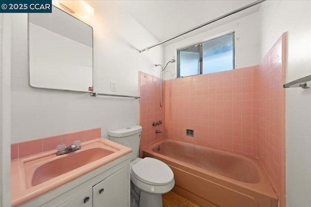 full bathroom featuring toilet, tiled shower / bath, and vanity