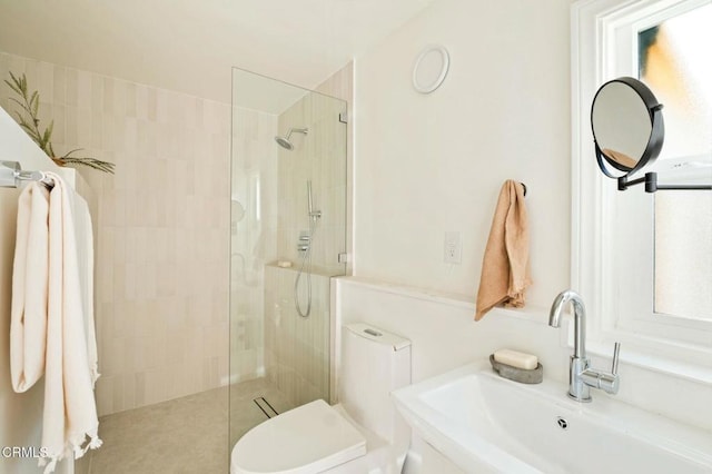 bathroom with sink, toilet, and a tile shower