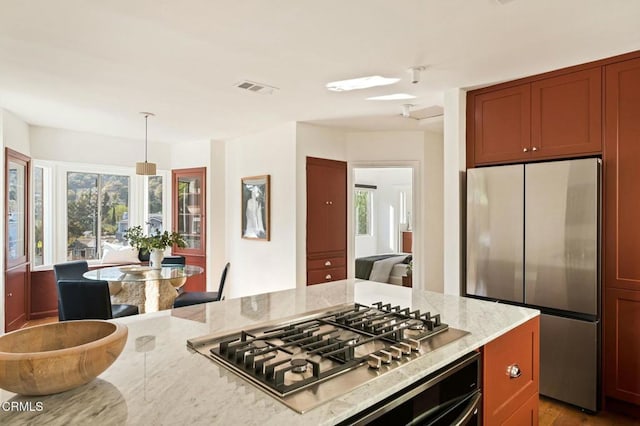 kitchen featuring appliances with stainless steel finishes, decorative light fixtures, and light stone countertops