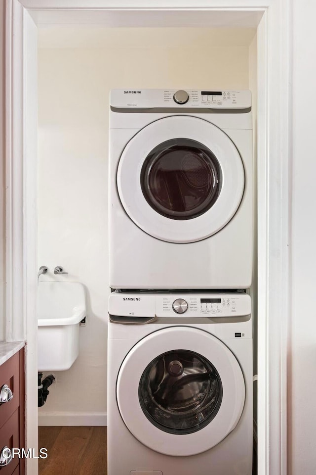 laundry area with dark wood-type flooring and stacked washer and clothes dryer