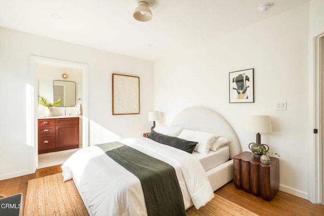 bedroom with light wood-type flooring and ensuite bath