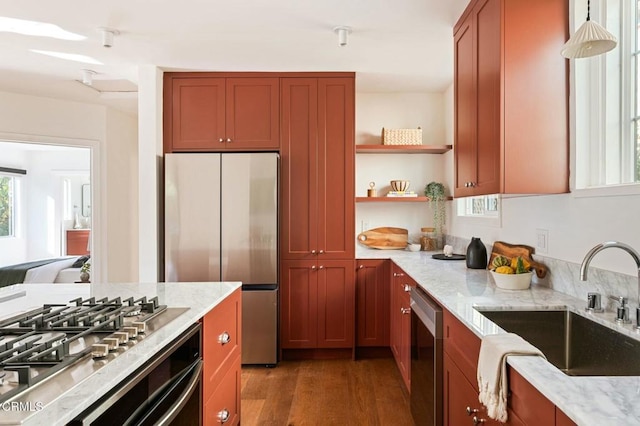 kitchen with appliances with stainless steel finishes, light hardwood / wood-style floors, light stone counters, and sink