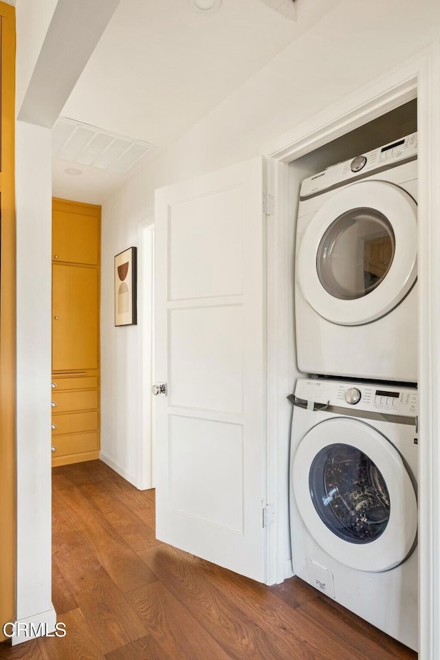 laundry area with stacked washing maching and dryer and hardwood / wood-style floors