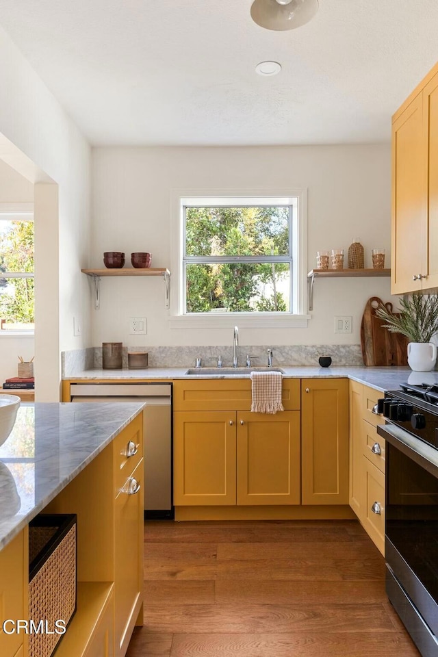 kitchen with light brown cabinetry, appliances with stainless steel finishes, sink, and light hardwood / wood-style floors