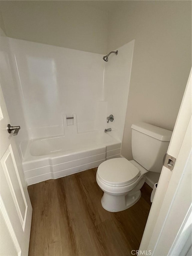 bathroom with wood-type flooring, toilet, and  shower combination