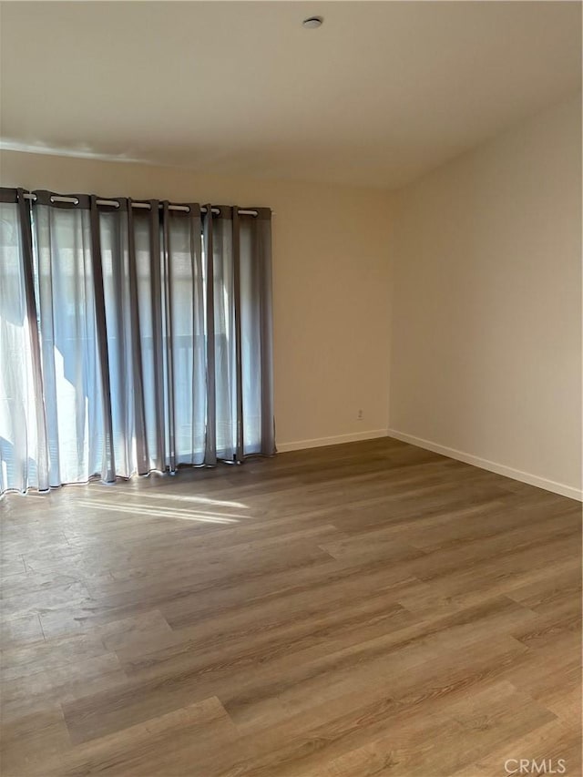 spare room featuring baseboards and wood finished floors