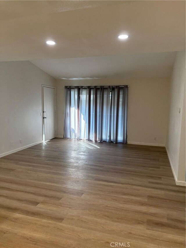 spare room featuring light hardwood / wood-style floors and vaulted ceiling