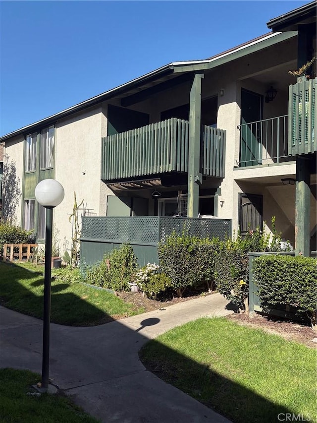 view of property exterior featuring a balcony and a yard