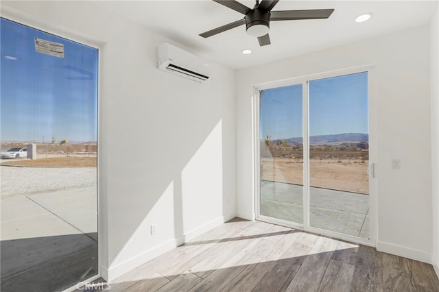 spare room featuring wood-type flooring, a wall mounted air conditioner, and ceiling fan