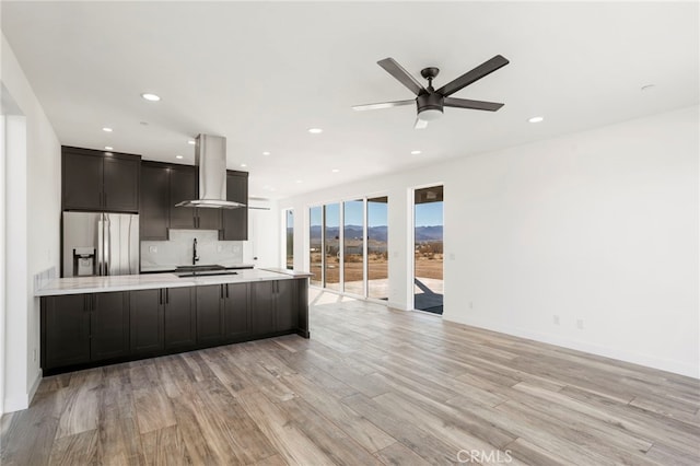 kitchen with sink, island range hood, light wood-type flooring, and stainless steel fridge with ice dispenser