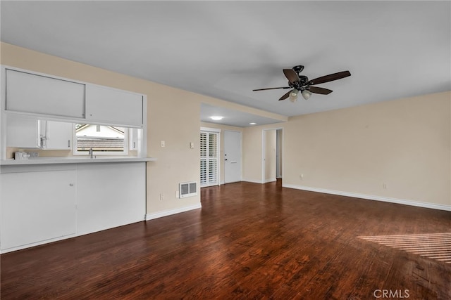 unfurnished living room featuring ceiling fan and dark wood-type flooring