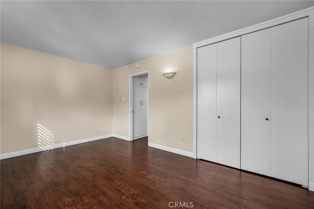 unfurnished bedroom with dark hardwood / wood-style floors and a closet