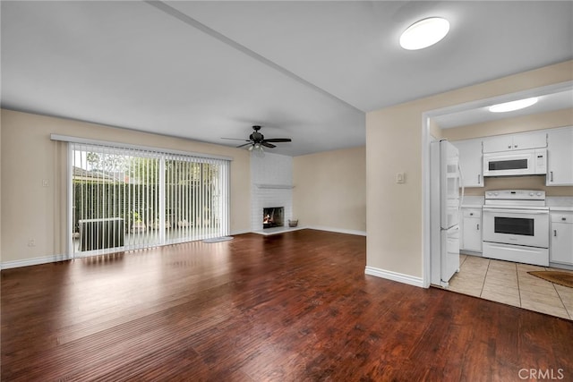 unfurnished living room featuring hardwood / wood-style flooring, a brick fireplace, and ceiling fan