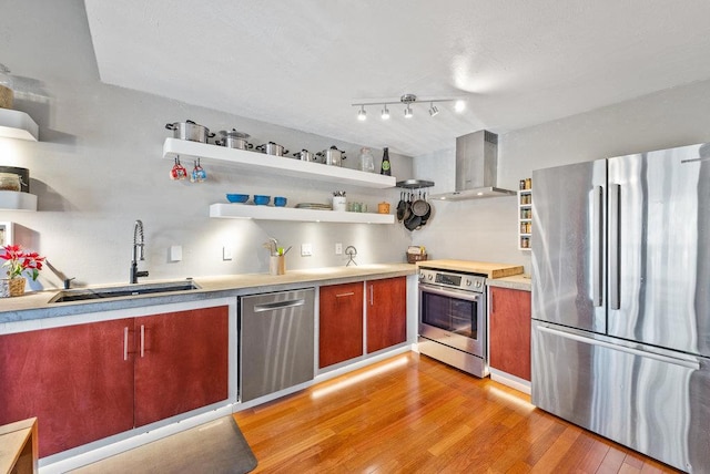 kitchen featuring light wood-type flooring, stainless steel appliances, sink, and exhaust hood