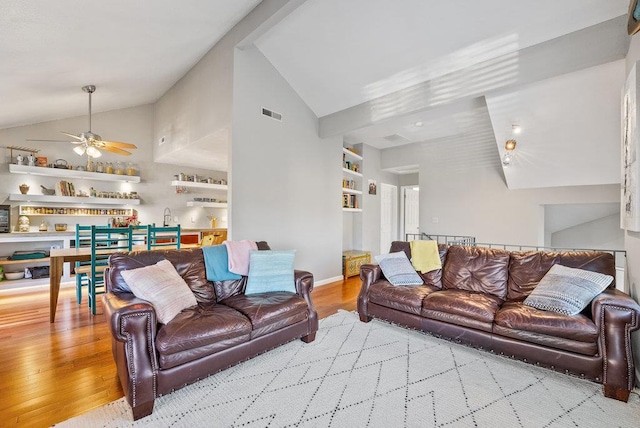 living room featuring ceiling fan, lofted ceiling, light hardwood / wood-style floors, and built in shelves