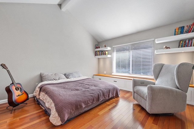 bedroom featuring light hardwood / wood-style flooring and vaulted ceiling with beams