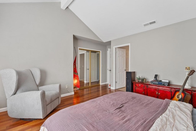 bedroom featuring hardwood / wood-style flooring, a closet, and lofted ceiling with beams