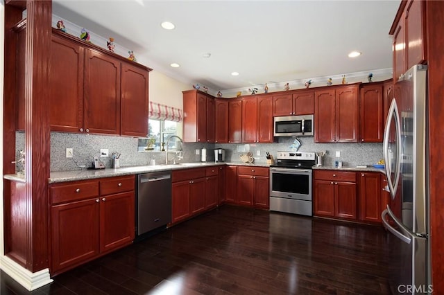 kitchen featuring appliances with stainless steel finishes, dark hardwood / wood-style floors, light stone counters, and sink