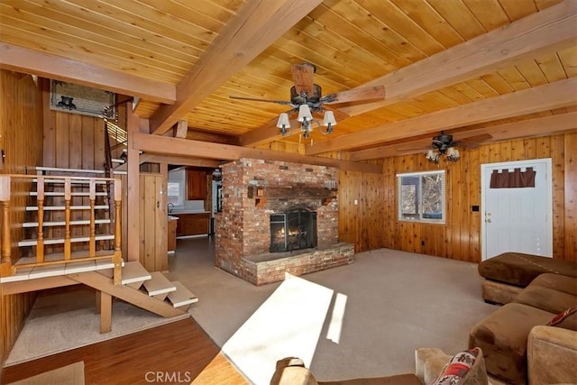 living room with beam ceiling, a fireplace, wooden walls, and carpet flooring