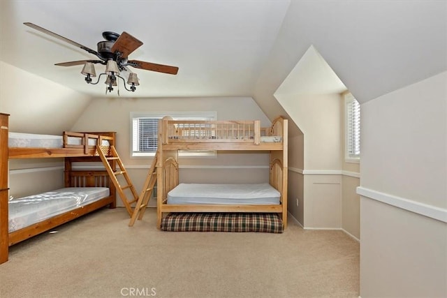 bedroom with ceiling fan, light colored carpet, multiple windows, and lofted ceiling