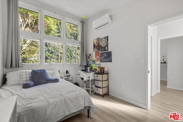 bedroom with a wall unit AC and light hardwood / wood-style floors