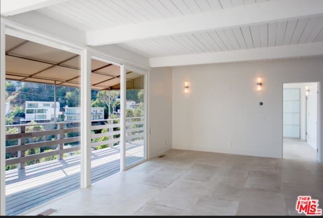 unfurnished room with beam ceiling