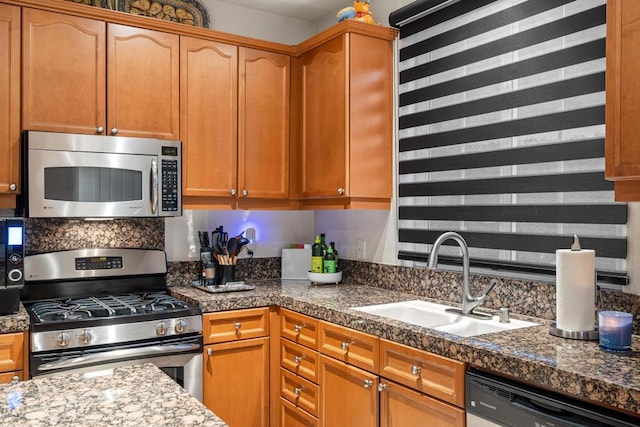 kitchen featuring sink, dark stone counters, and stainless steel appliances