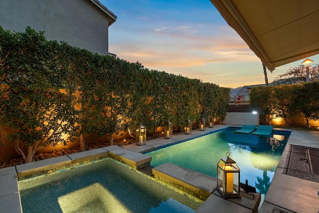 pool at dusk featuring an in ground hot tub