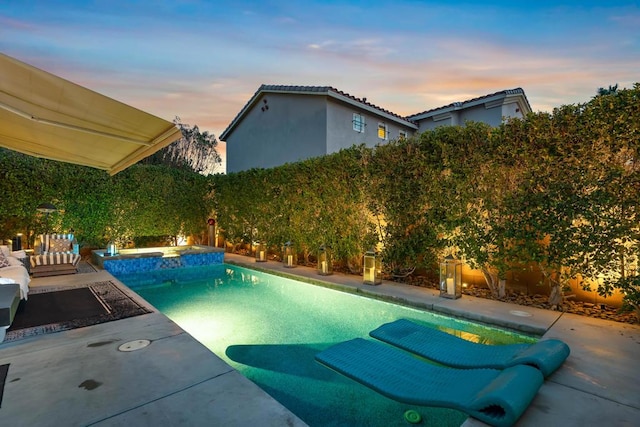 pool at dusk featuring an in ground hot tub and a patio area