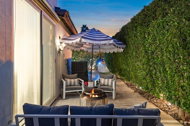 patio terrace at dusk featuring an outdoor living space with a fire pit