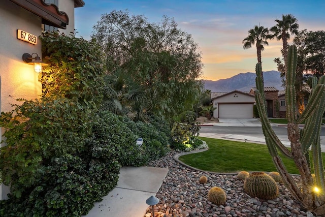 view of front of property with a mountain view, a garage, and a lawn