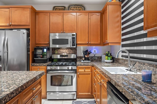 kitchen featuring sink, stainless steel appliances, dark stone countertops, and light tile patterned floors