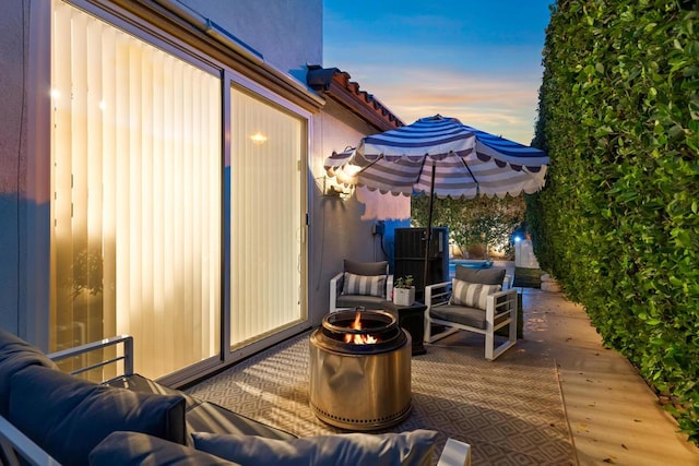 patio terrace at dusk featuring an outdoor living space with a fire pit