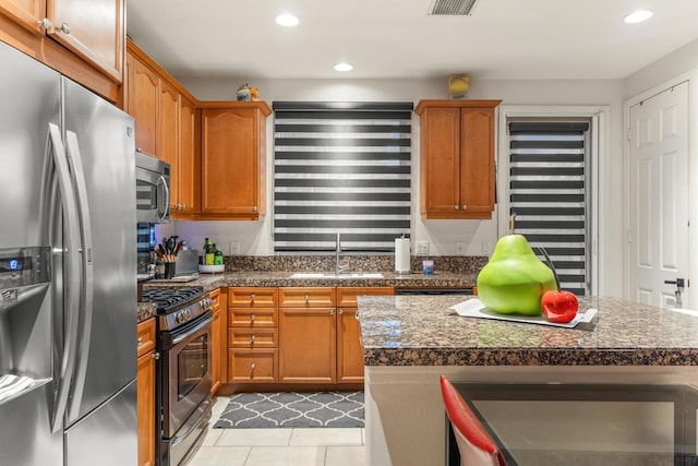 kitchen with sink, stainless steel appliances, a center island, and light tile patterned floors