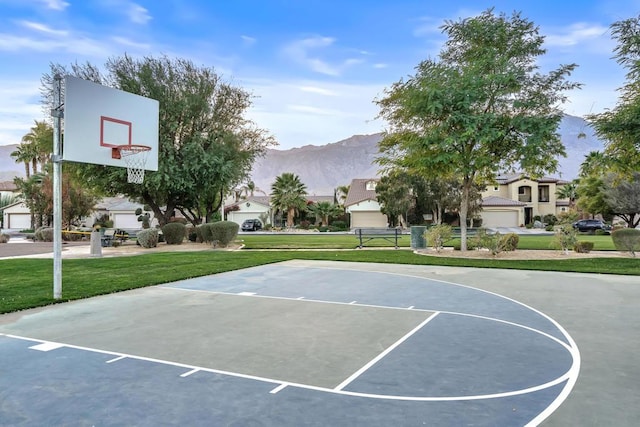 view of sport court featuring a mountain view and a lawn