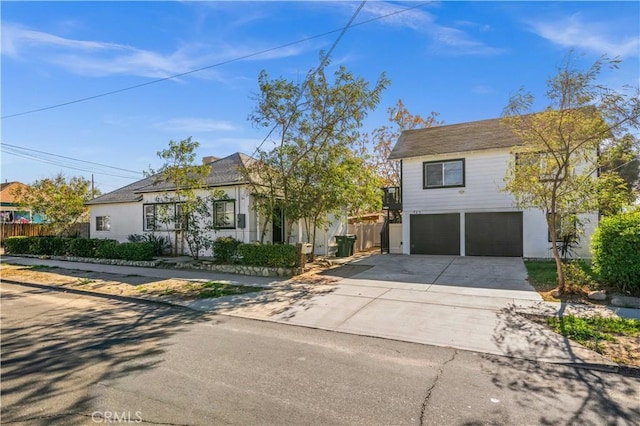 view of front of house with an attached garage, fence, and concrete driveway