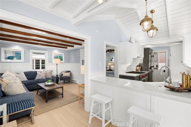 kitchen with high end stainless steel range, white cabinets, decorative light fixtures, and light hardwood / wood-style floors